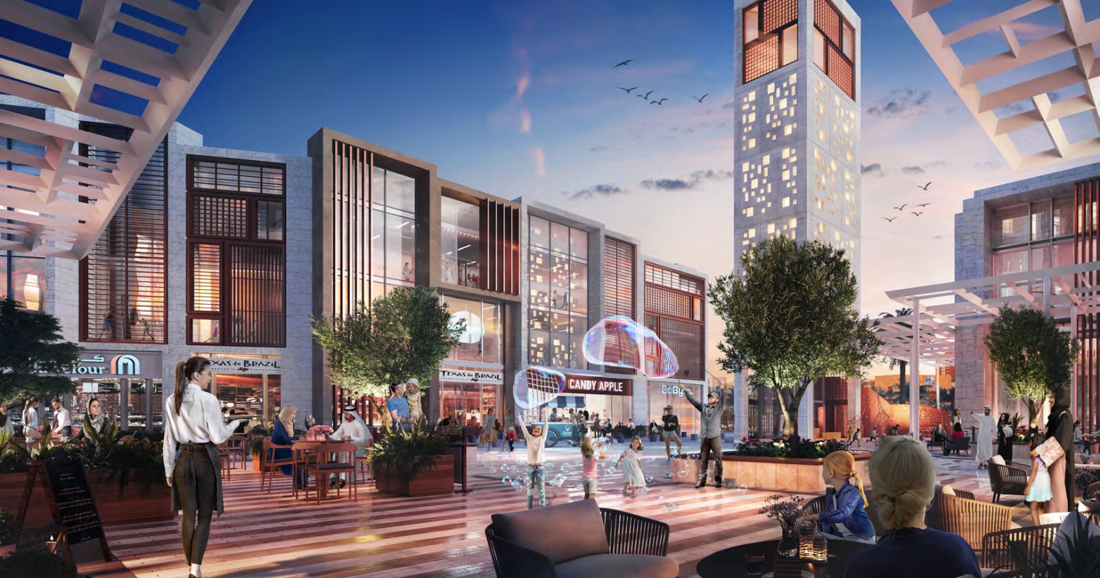 Evening view of a dining and retail street with cafes and shopfronts at Uptown Zahia